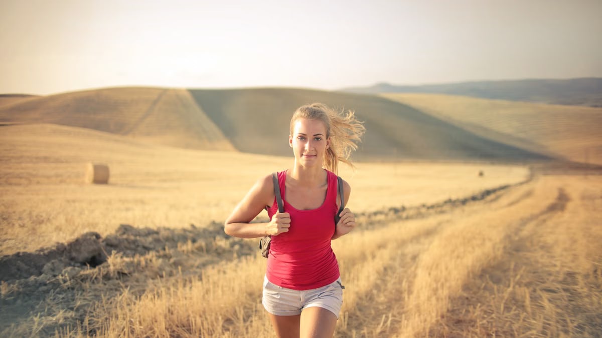 A woman jogging through vast, golden wheat fields under the summer sun, symbolizing freedom and adventure.